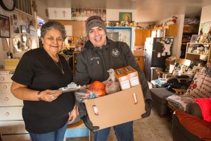 Young Indigenous man bringing a box of groceries to an older woman