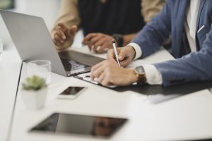 Close up image of the hands of two people working at a laptop computer