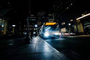 Image of a city bus driving quickly down a city street late at night.