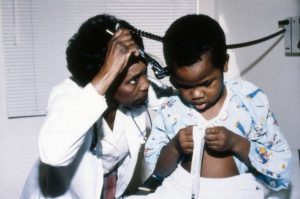 doctors performing physical examinations on patients, looking into ear with otoscope