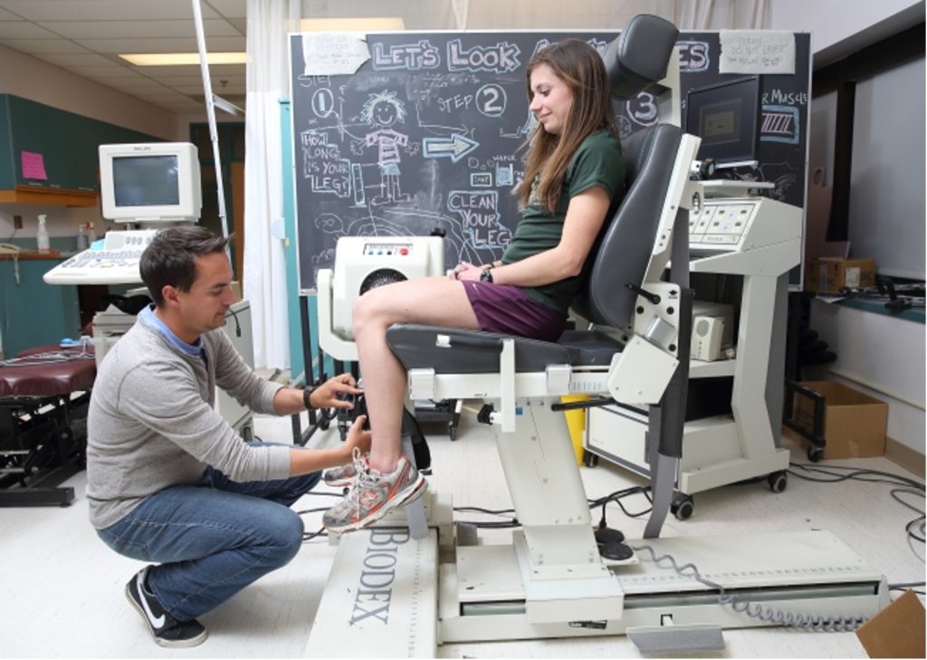 Scientists adjusting position of female subject on Biodex chair