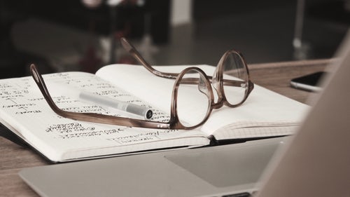 photo of a pair of glasses resting on a notebook