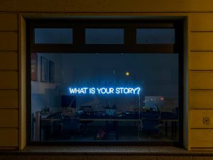 What is Your Story? in neon letters in a window