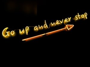 Go up and never stop neon sign with arrow.