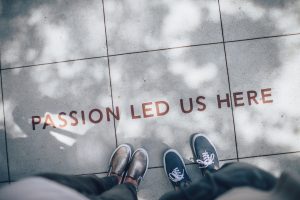 two feet standing on a gray tile reading "Passion led us here"