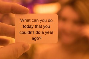 hand holding slip of paper that reads "What can you do today that you couldn't do a year ago?"