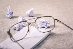 glasses on a notepad and crumpled up pieces of paper