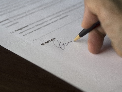 Photo showing someone signing the signature page of a contract