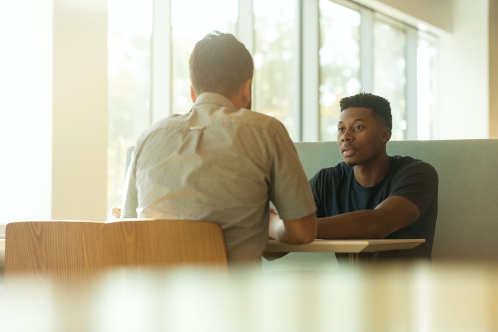 A young man sit across the table from another person