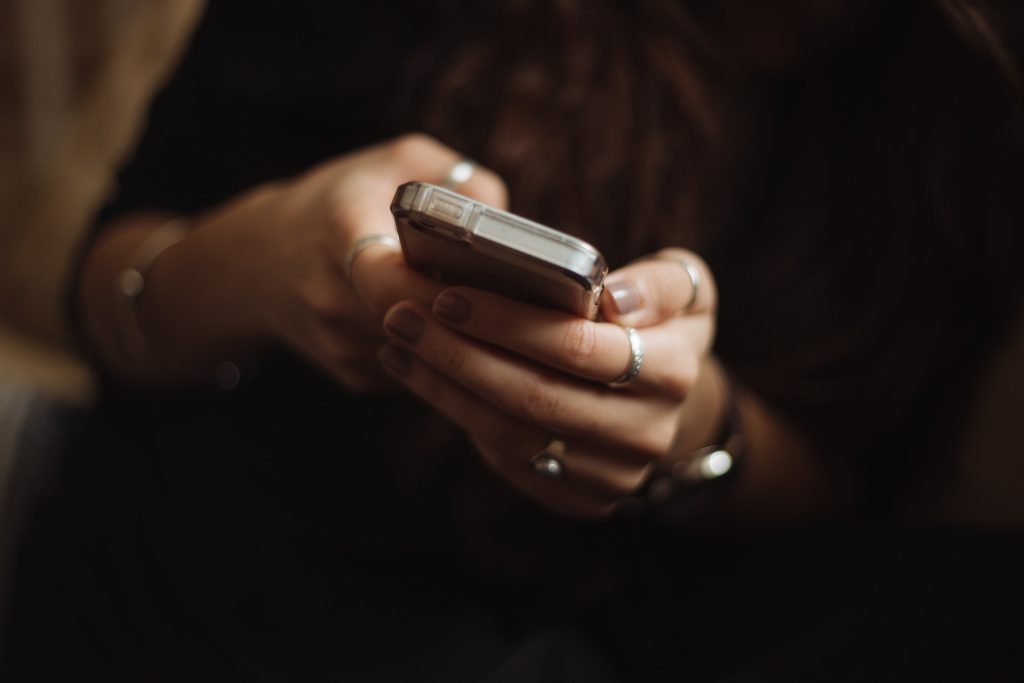 A person using a smartphone--they have it clasped in both hands and appear to be texting.