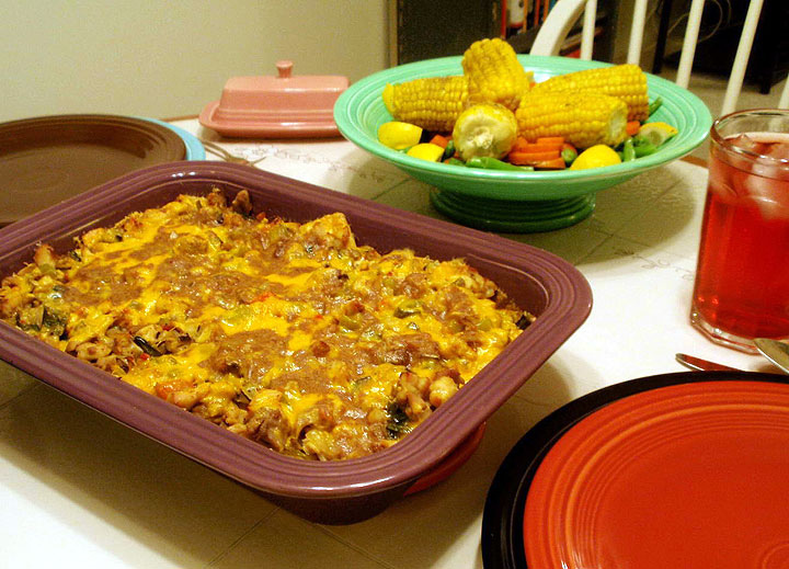 King Ranch Chicken casserole  on a table with a bowl of mixed vegetables. All very tasty looking.