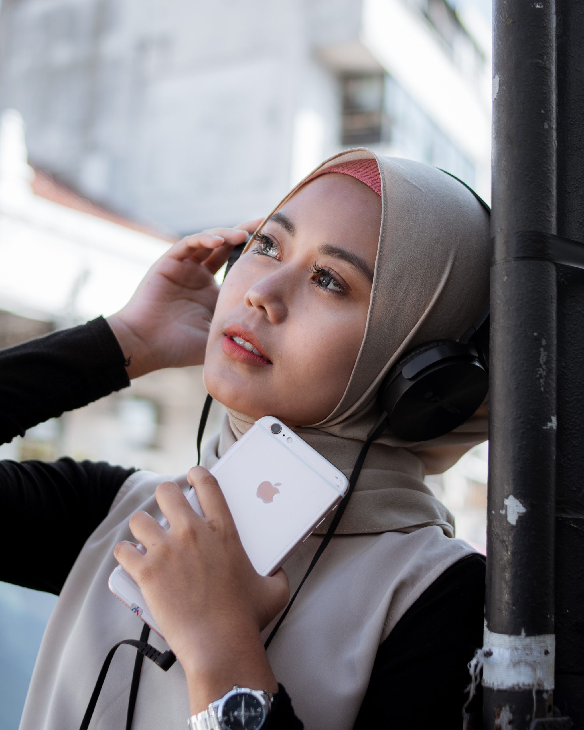 woman holding iphone and wearing headphones