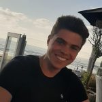 young man dark short hair smiling and wearing a black t-shirt