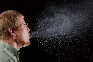 image of someone sneezing and the droplets that result