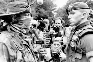 Soldier speaking with an Indigenous protester during the Oka Crisis, with media photographers visible in the background