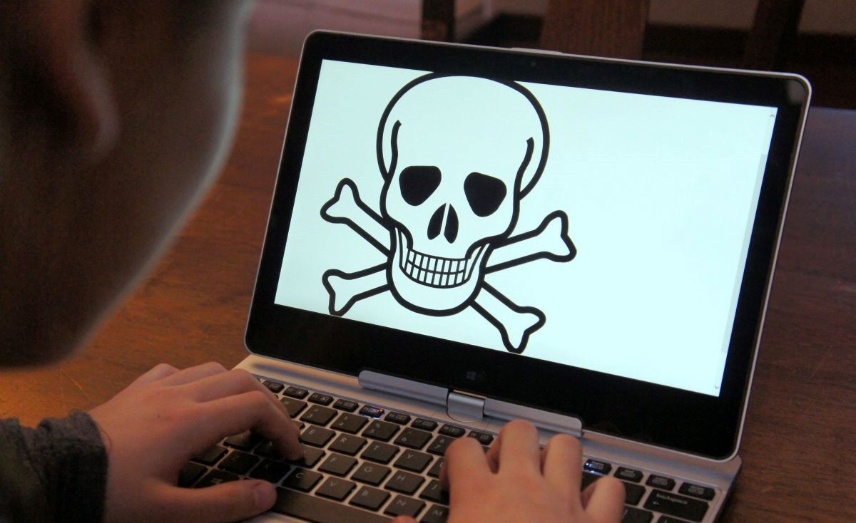 Student looking at crossbones and skull on his laptop.