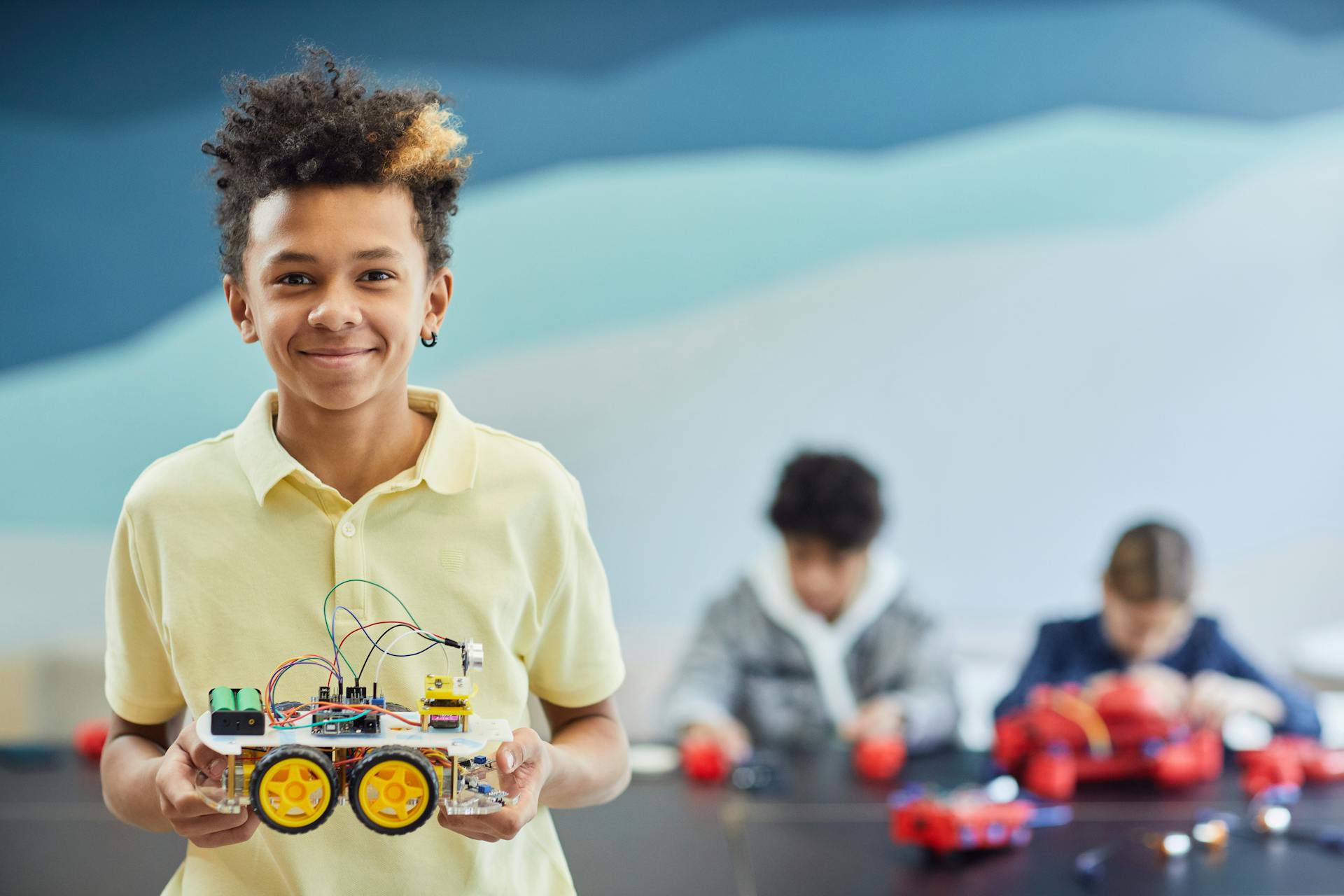 A boy holding a robot vehicle that he has just built.