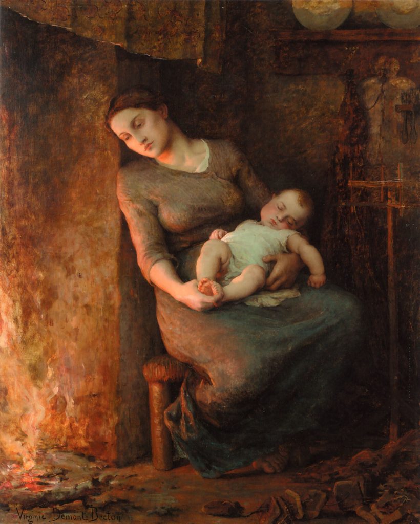 A woman leans against the hearth of a fireplace while seated on a chair with a sleeping infant in her lap