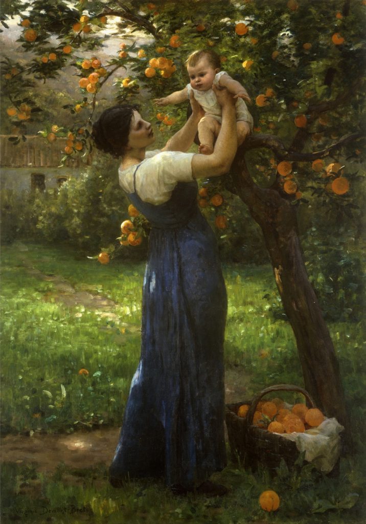 A woman dressed in a blue dress with a white short sleeve shirt beneath it lifts an infant over her head towards the oranges on the tree infront of them. At her feet a basket full of oranges sits.