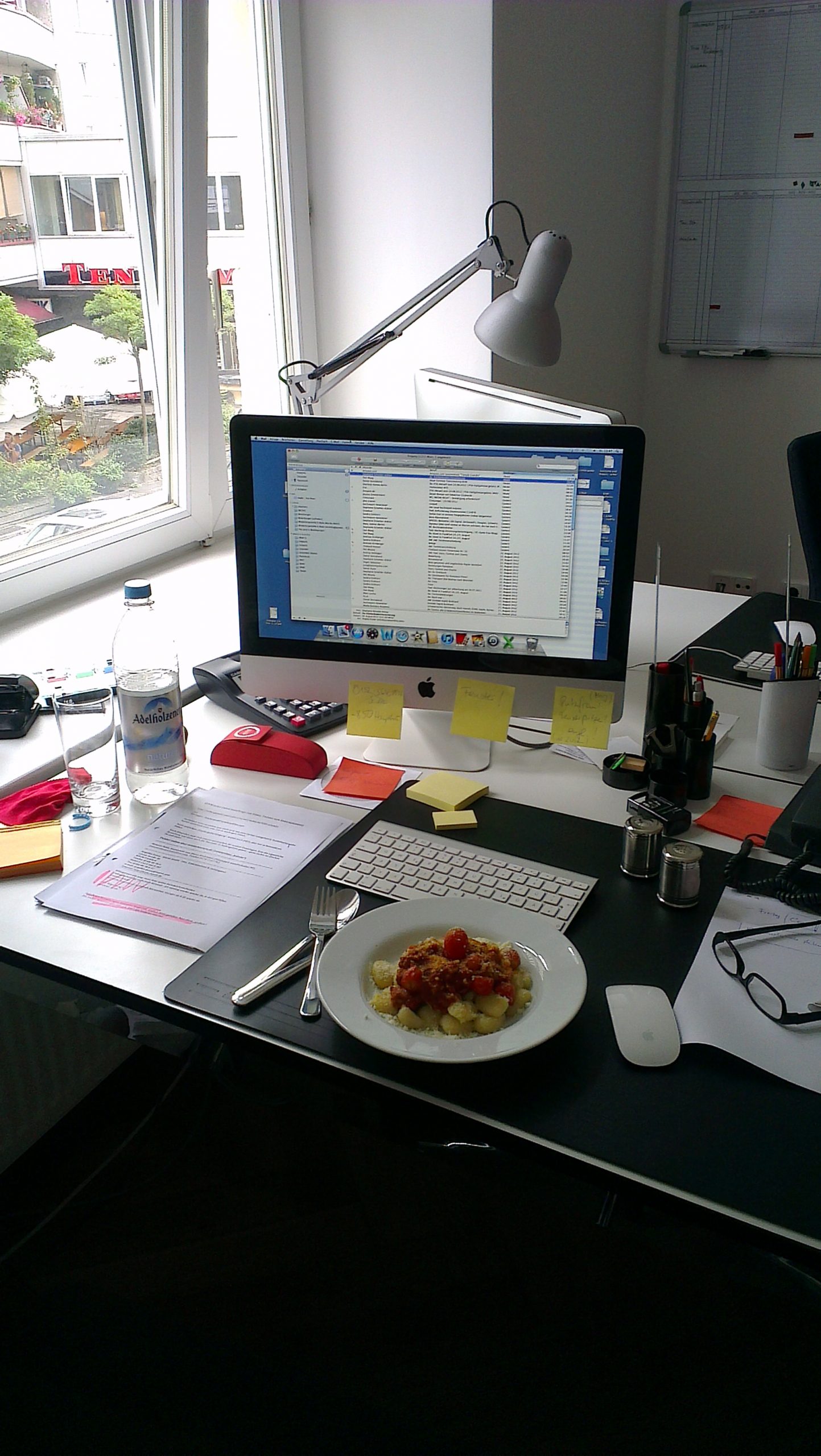 Descriptive image showing a plate of food on a work desk in front of a computer monitor.