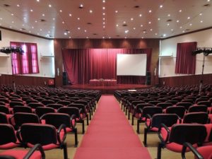 Descriptive image showing the view of a stage from the back of an empty auditorium.