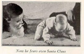 A photograph shows a man wearing a mask with a white beard; his face is close to a baby who is crawling away. A caption reads, “Now he fears even Santa Claus.”